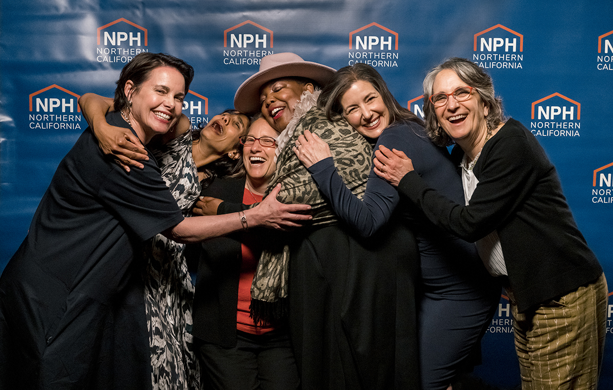 Group of past speakers and awardees smiling and laughing with Amie of NPH