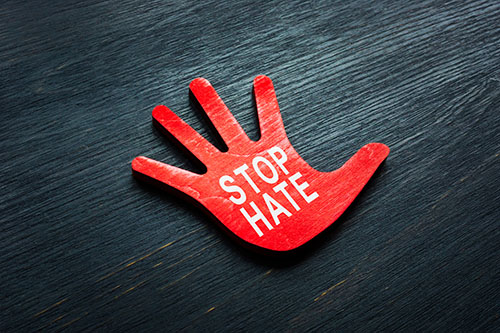 A red hand on a black background with Stop Hate written on the palm.