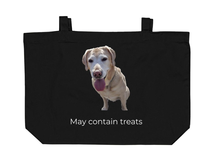 A black tote bag with a picture of a Golden Labrador service animal. The words may contain treats appear below the dog.