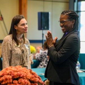 Able SC staffer talks with a Summit attendee- a white woman from Able SC listens attentively while a Black woman from Dominion Energy smiles with hands together.