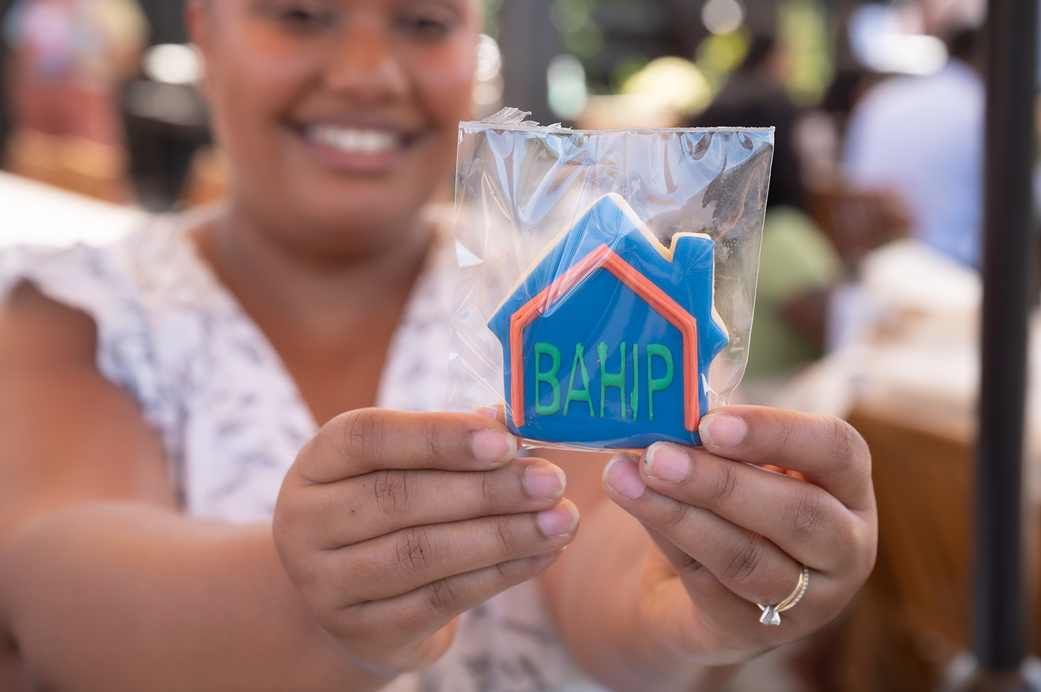 Photo of Izanie holding a BAHIP cookie that is in-focus in the foreground