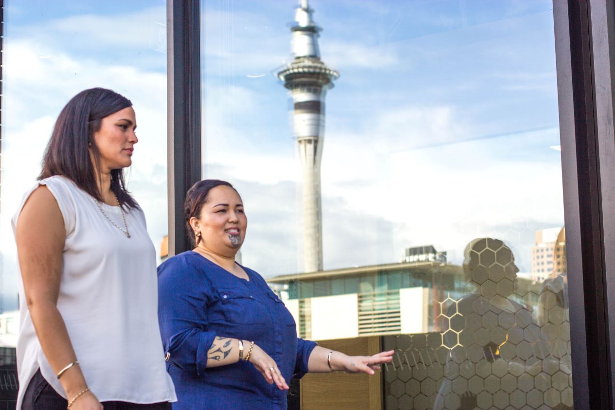 Women walk by the Sky Tower in Auckland.