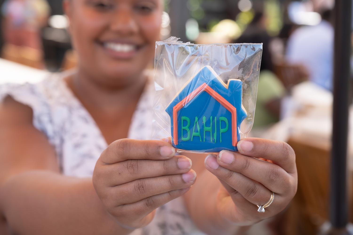 Close up of a cookie in the shape of a house with BAHIP written in icing