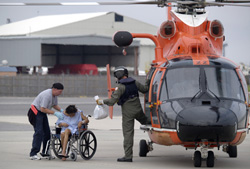 An individual using a wheelchair being assisted into an emergency helicopter.