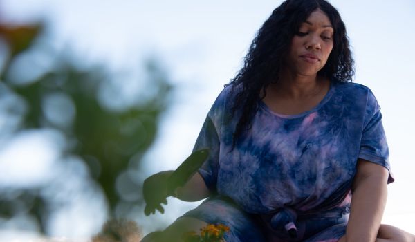 Image: A woman affected by obesity sits down in the grass to garden