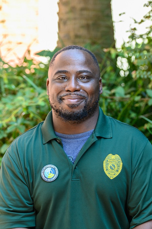 A Black man with an 'I'm vaccinated' button, smiling outside.