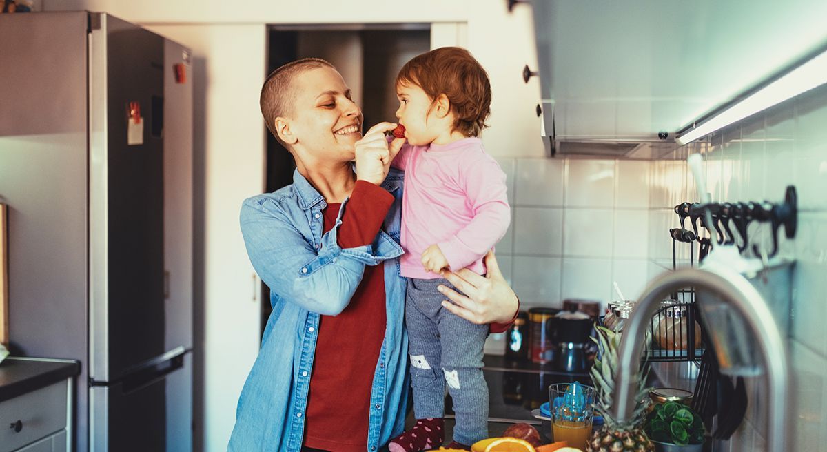 A mother feeds her daughter a strawberry