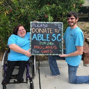 Able SC staff holding a chalk board sign that says