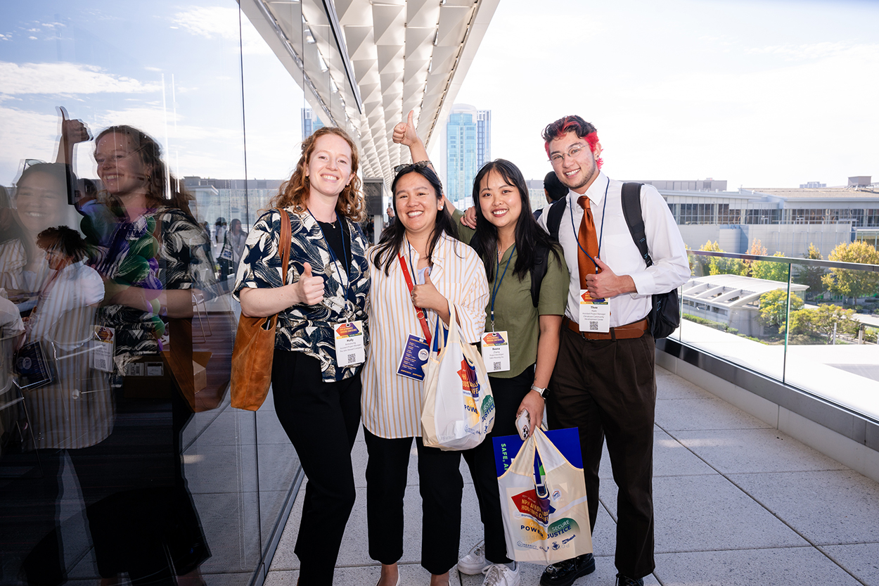 4 people posing outside with Conference items