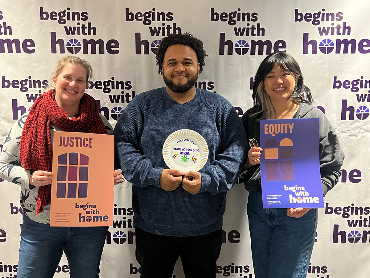 EBHO staff posing in front of Begins with Home background