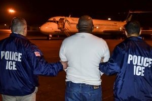 A migrant scheduled to be deported from the United States is escorted to a charter flight.