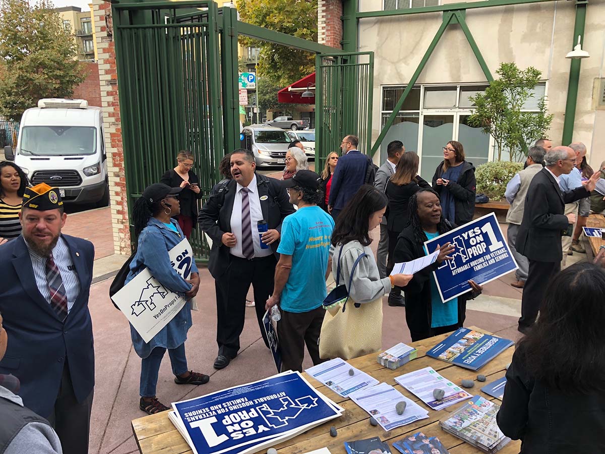 People outside of a development prior to a rally with political signs on a table