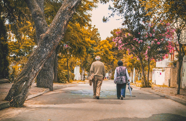 Older man and woman walking through neighborhood in fall