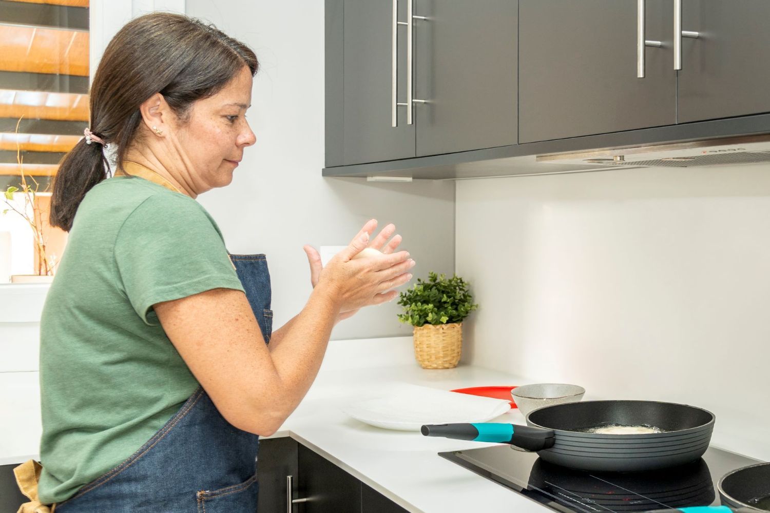 A woman makes arepas in the kitchen.