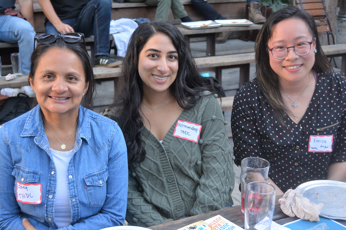Image of three members at ELPN event, outdoors at wooden table