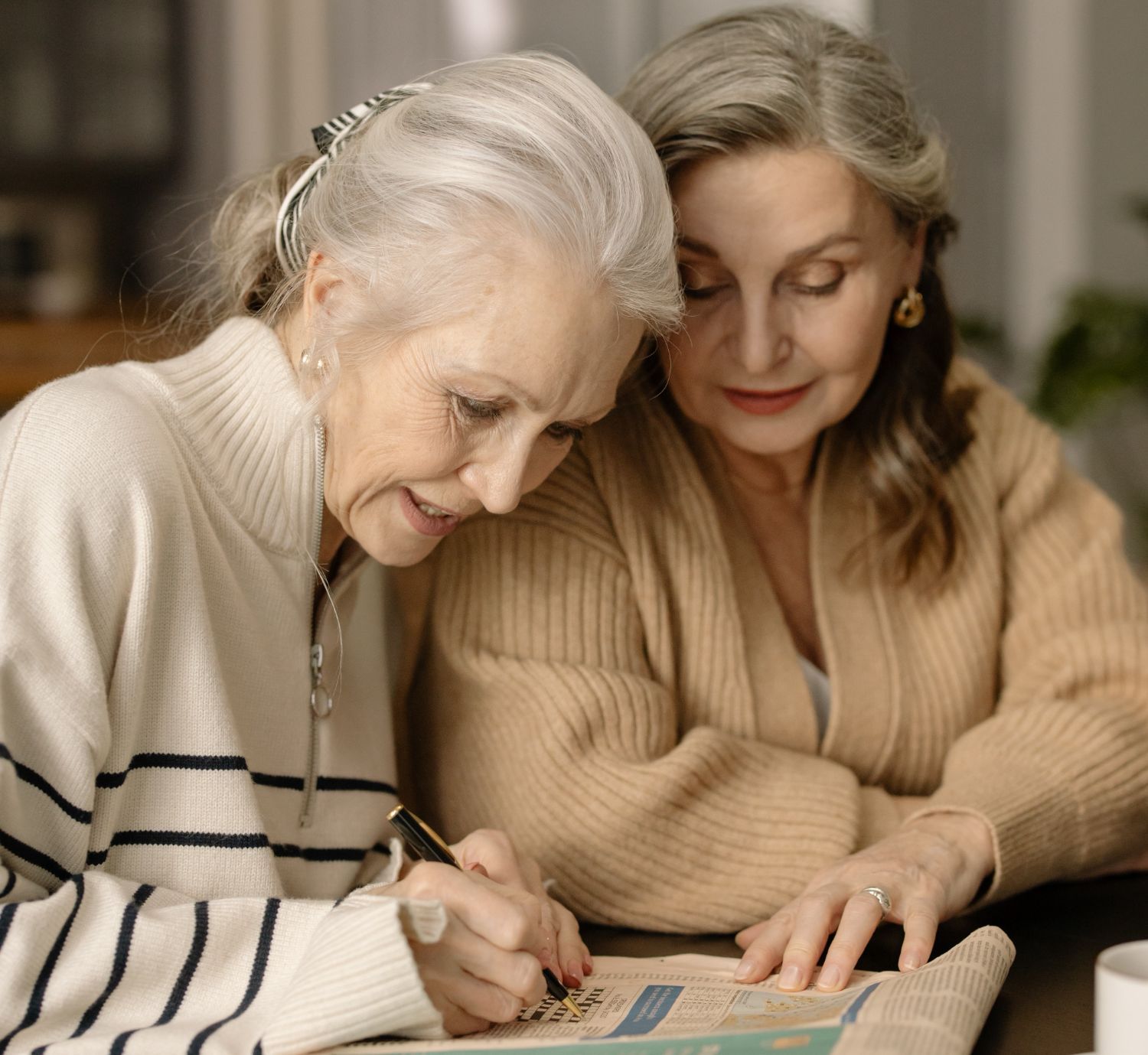 Two older adult women working on a document