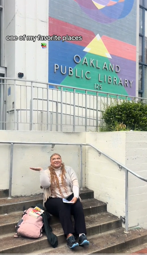 Image of person sitting on stairs in front of Oakland library