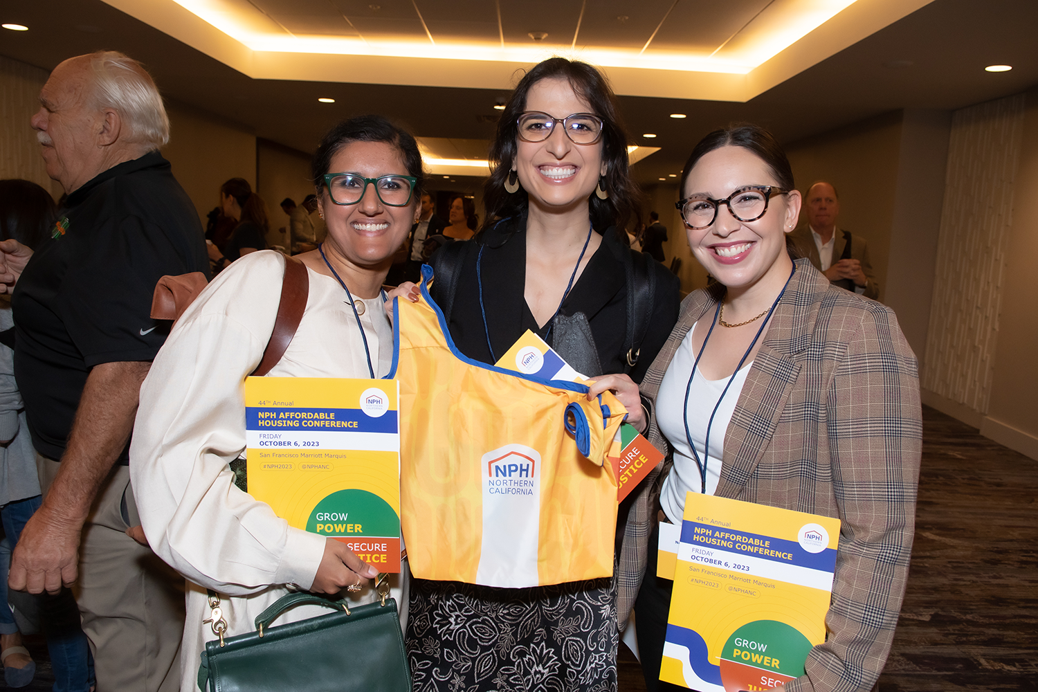 Three people holding NPH conference items