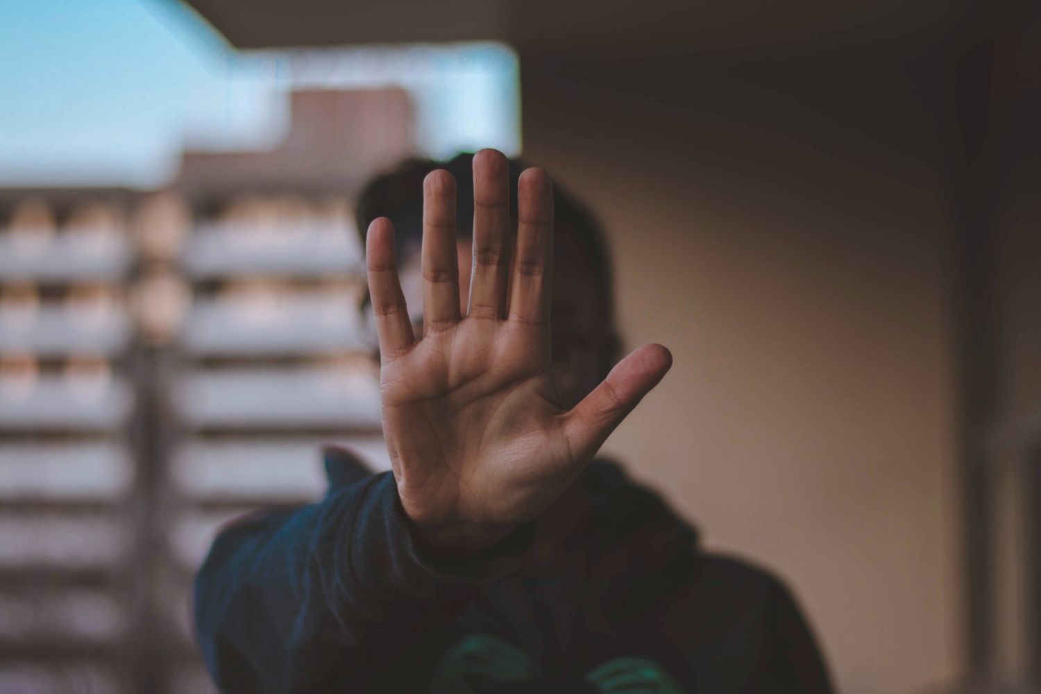 An individual with their hand raised toward the camera indicating stop.