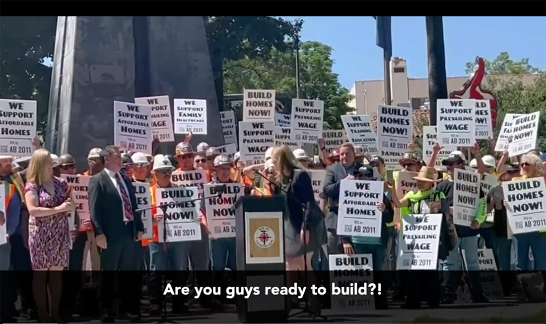 AB 2011 rally with Buffy Wicks at podium and carpenters behind her holding signs.