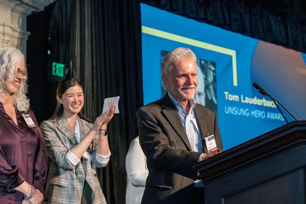 Awardee on stage smiling as they receive an award
