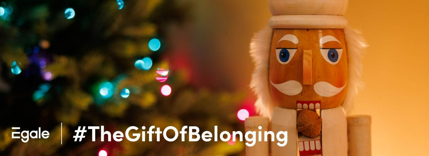 Headshot of nutcracker with a chestnut in its mouth. The Egale logo is in the bottom left hand side, with the hashtag #TheGiftOfBelonging to the right of it.