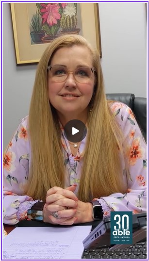 Screenshot of video of Mandy, a white woman with long blonde hair sitting in her office, hands clasped and looking pleasant.