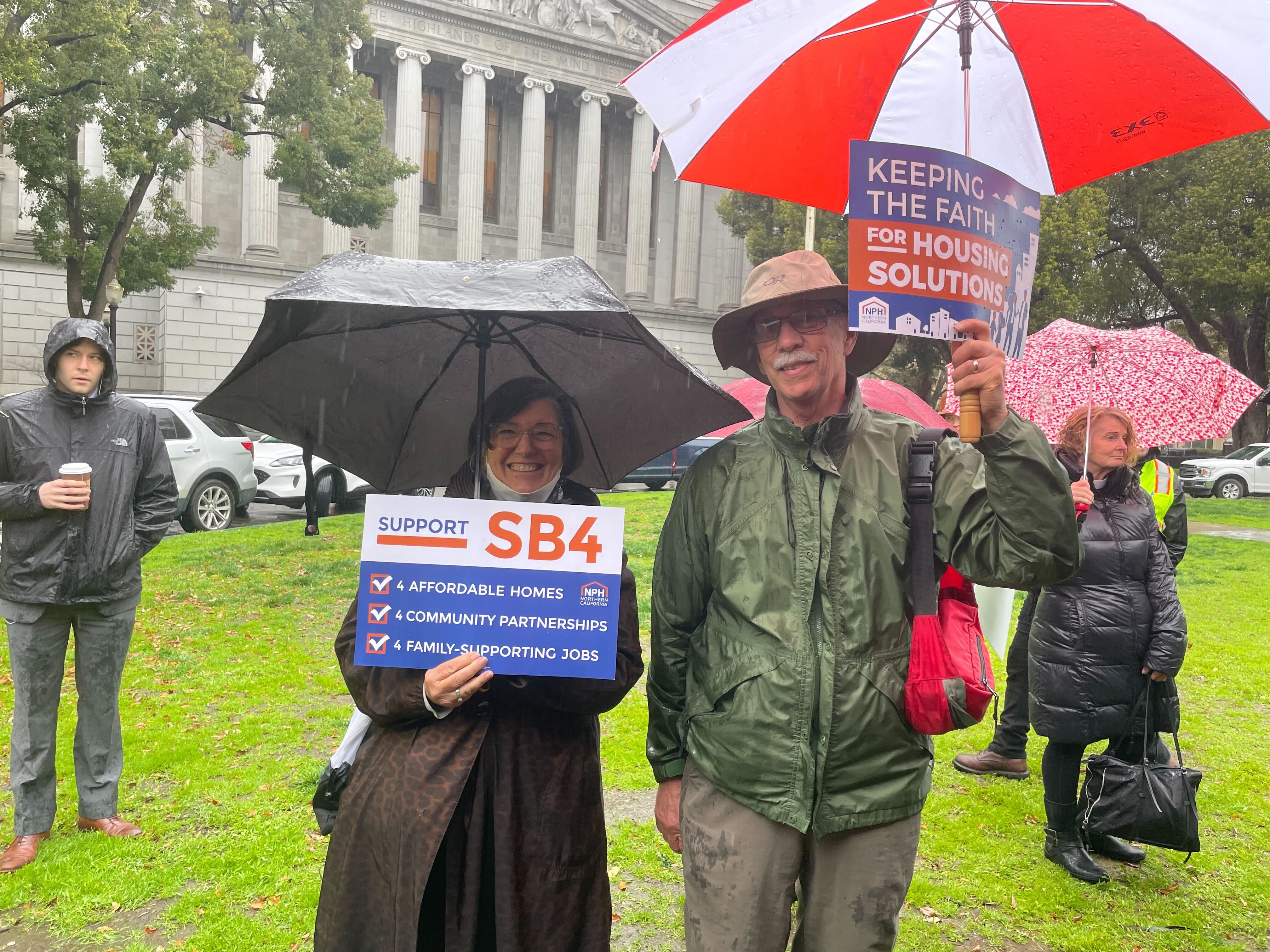 Two people holding an SB4 sign