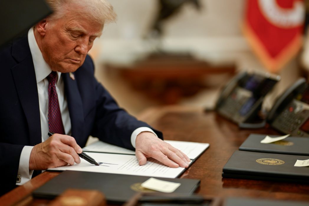 President Donald Trump signs an executive action at the White House.