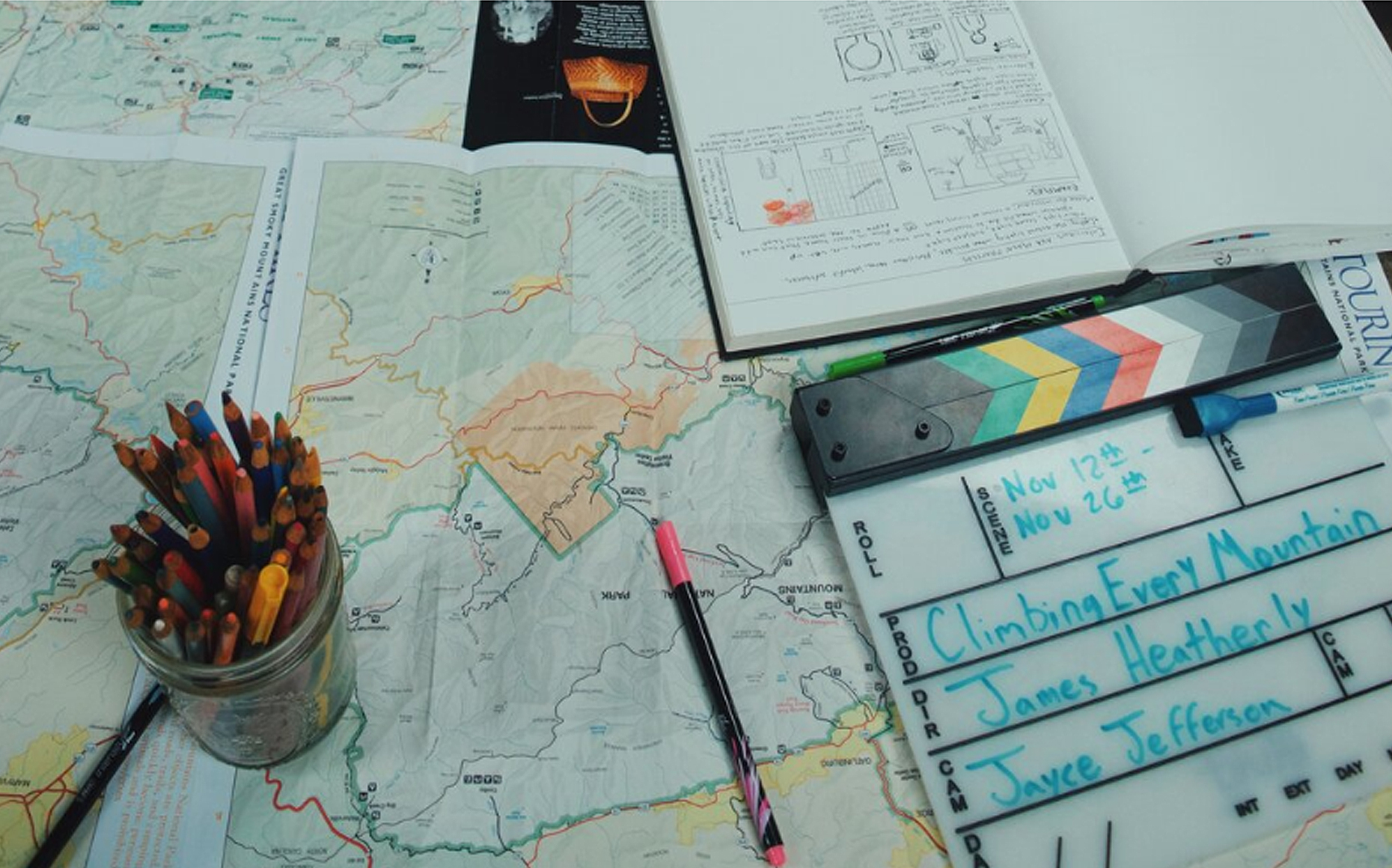 A map of Appalachia with art supplies and a film clapboard sitting on top of it