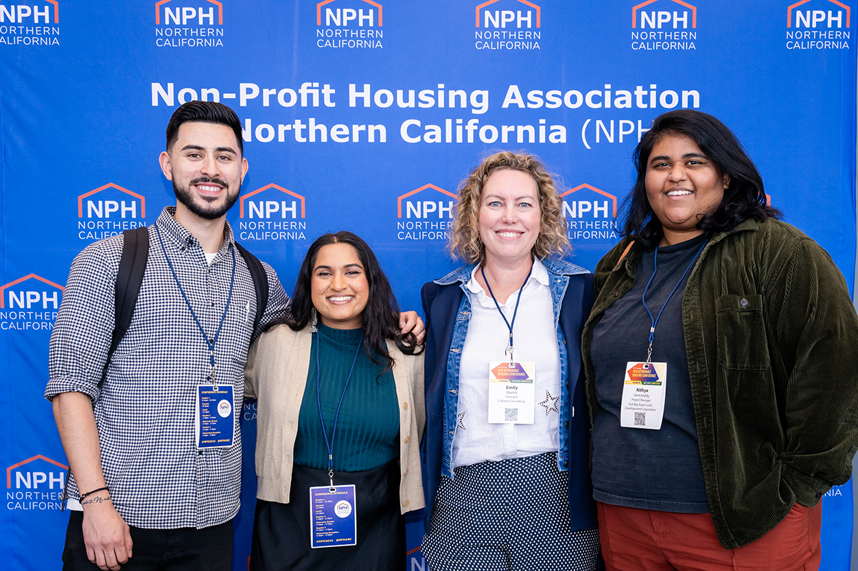 Four people posing in front of an NPH-branded backdrop