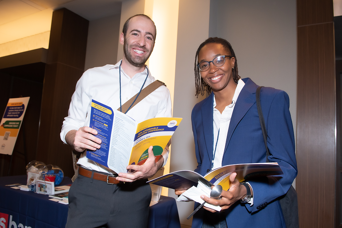 Two members holding programs from the NPH conference and smiling at camera
