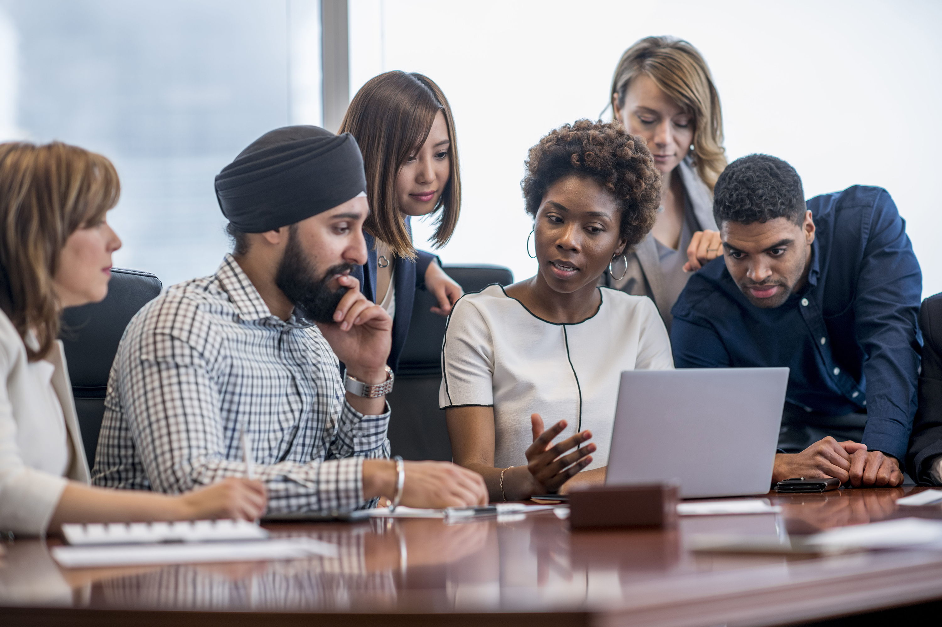 Group of diverse individuals looking at a computer screen